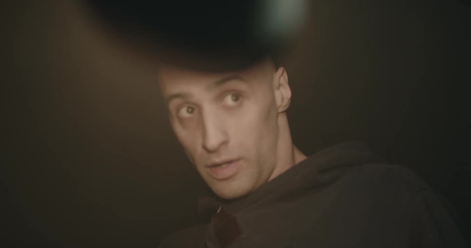 A detective turns a bright lamp into a suspects face during an interrogation