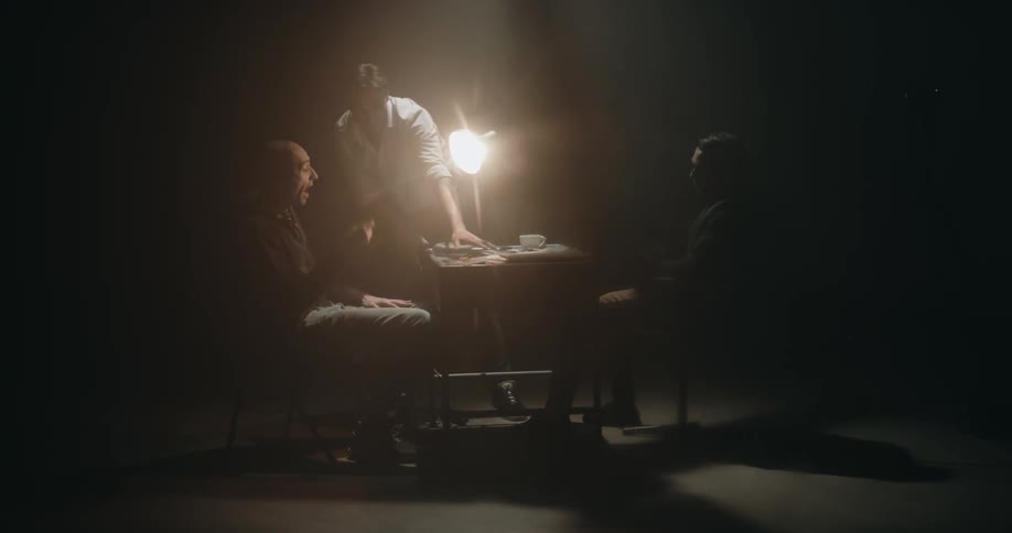 Man aggresively interrogates suspect sitting on a chair inside an interrogation room