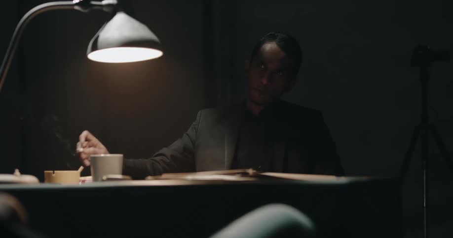 A man is smoking a cigarette and drinking coffee