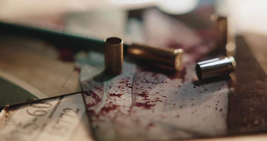 Bullet shell casings sit on top of photos of blood spatter at a crime scene