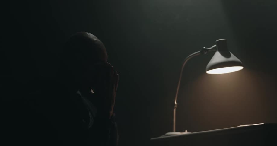 A man is holding his face in the dark room