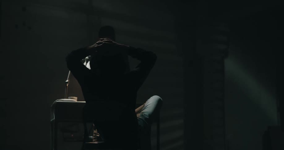 Silhouette of a suspect leisurely sitting on a chair inside an interrogation room