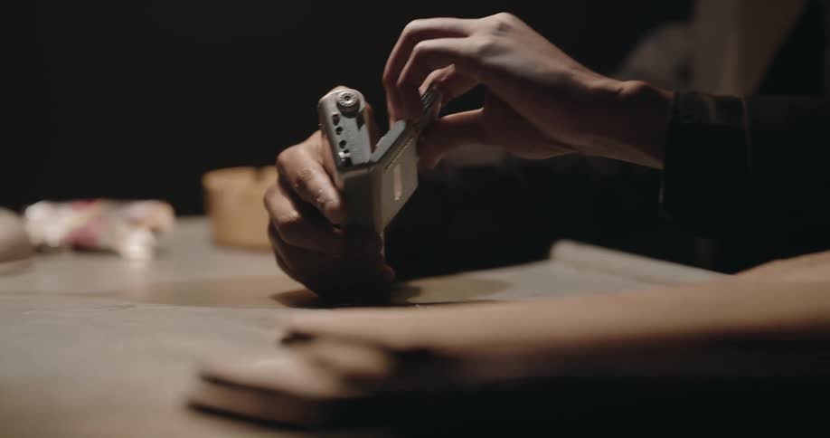 Man changes the tape on a portable recorder over a desk