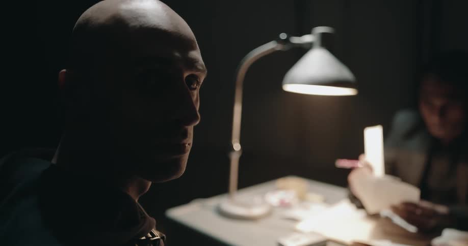 Two men are talking at a table indoors at night