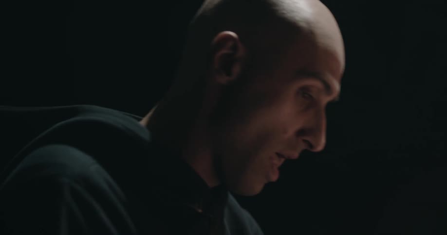 Two men are talking in a dark lit room