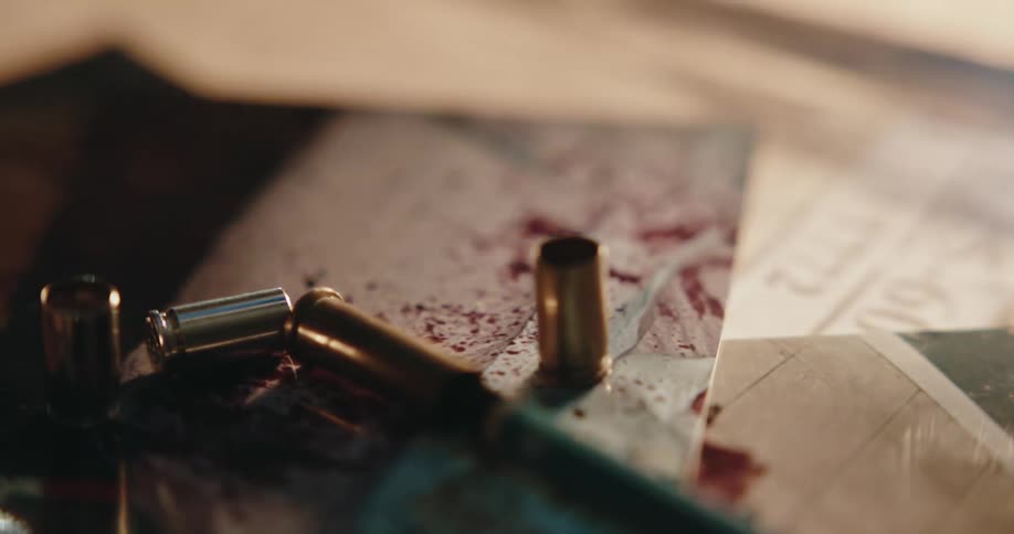 Bullet casing over the pictures of a gruesome crime scene over a desk