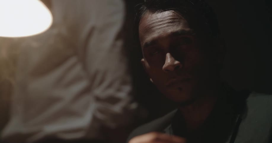 A man smokes a cigarette in the dark room