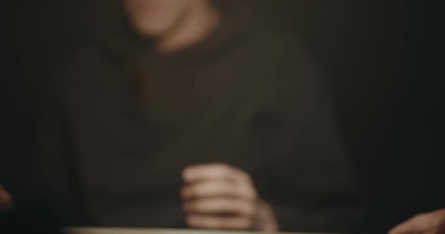 Detective aggressively shakes pictures in front of a suspect inside an interrogation room