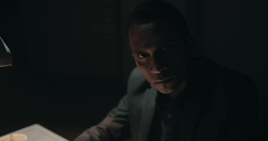 A man is sitting at a table in a dark lit room