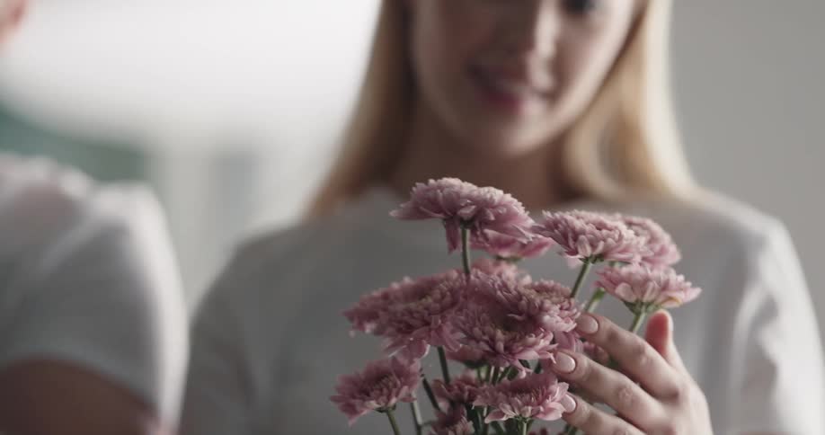 Woman handles flowers and man arrives to hand a bouquet to her