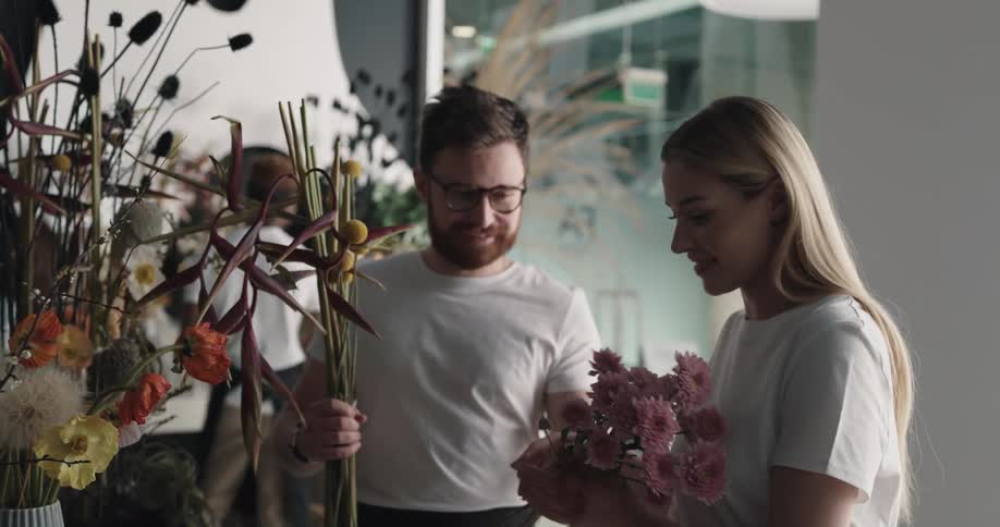 Two people talk and laugh as a group is making floral arrangements