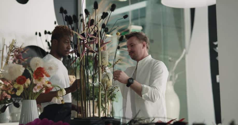 Two men are creating a flower arrangement in a flower shop