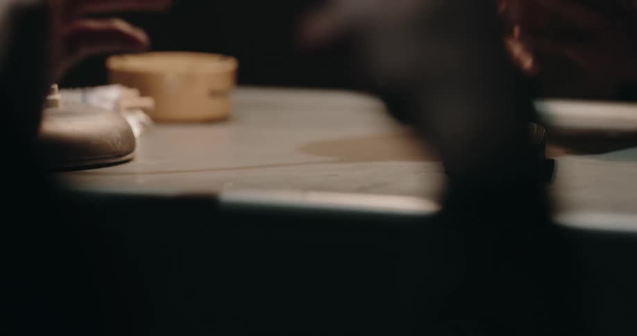 Detective puts a cassette tape into a recorder over a desk inside an interrogation room