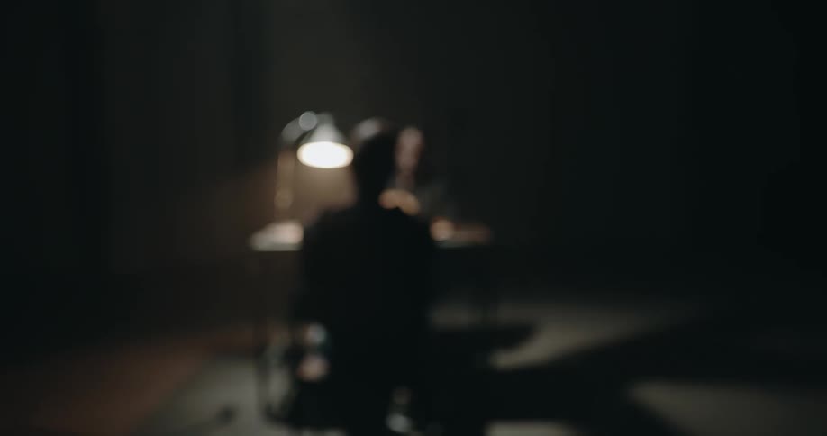 A man is being interrogated in the small room