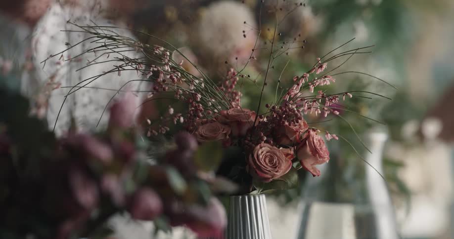 People are talking animatedly with their hands near a flower arrangement