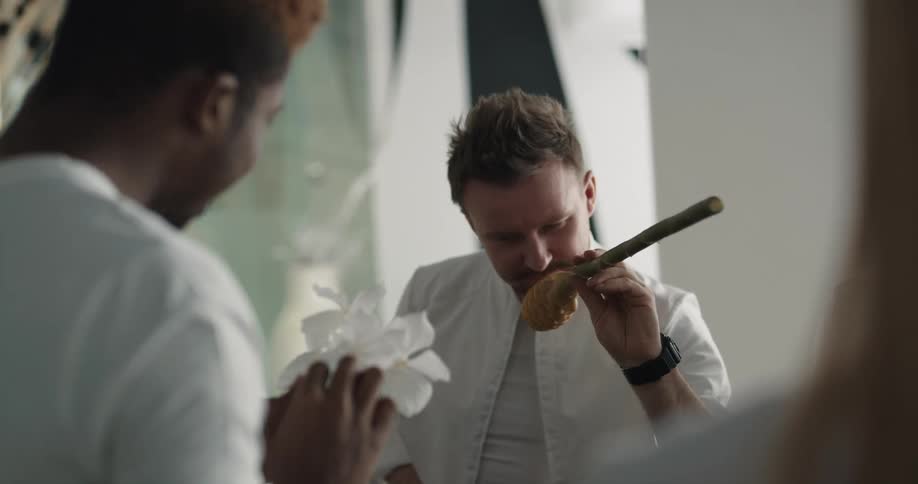 A man smells a flower and hands it off