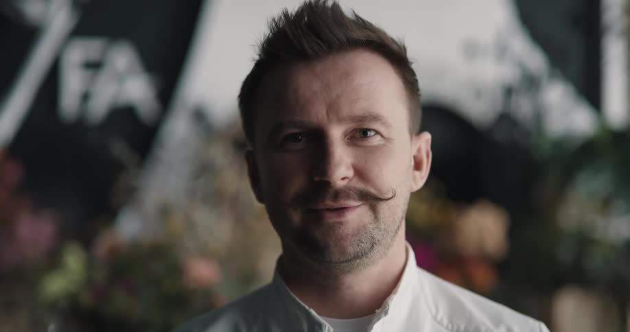 Owner of a flower shop with a mustache looking at the camera