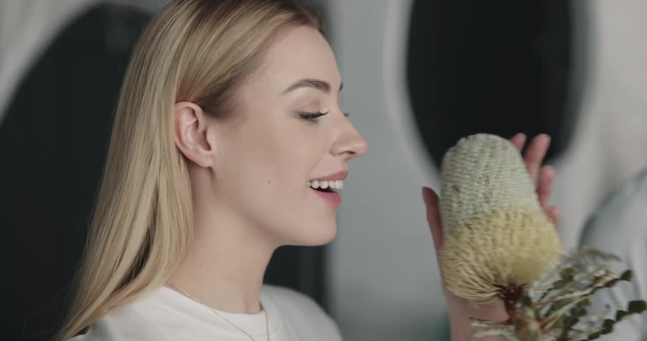 A woman lifts and smells a flower