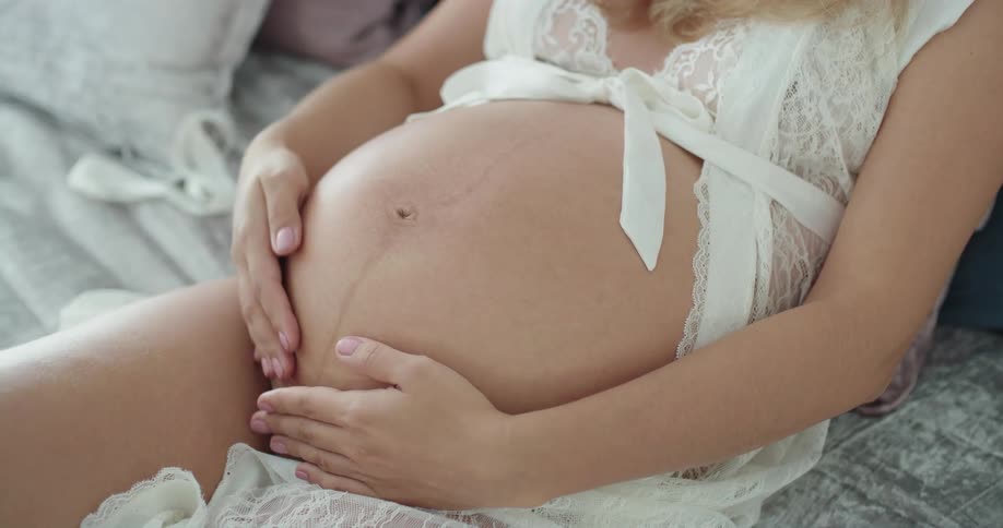 A woman is rubbing her pregnant stomach