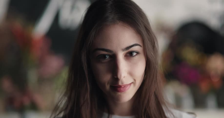 A woman is smiling inside a flower store