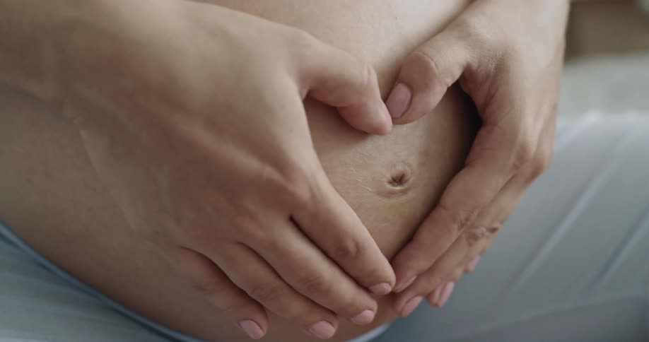 Pregnant mother gently rubs and massages her belly with both hands