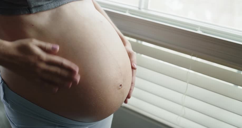 Young pregnant woman is rubbing her belly