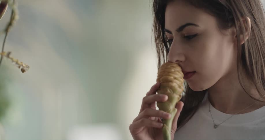 A woman smiles as she smells a flower