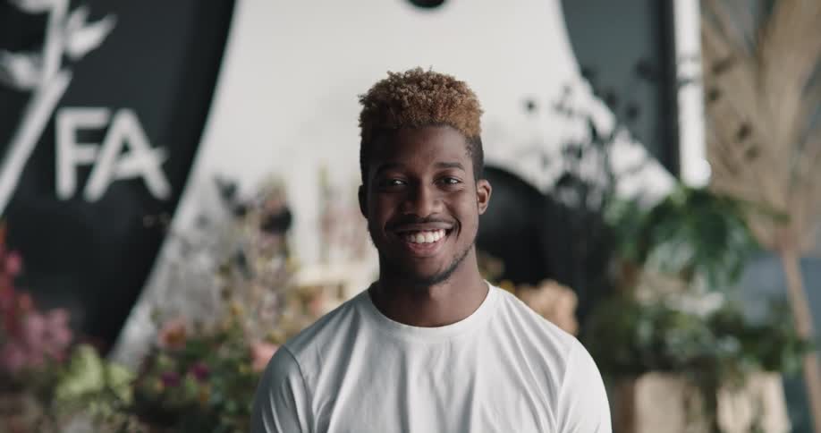 A young man raises his head to smile into the camera