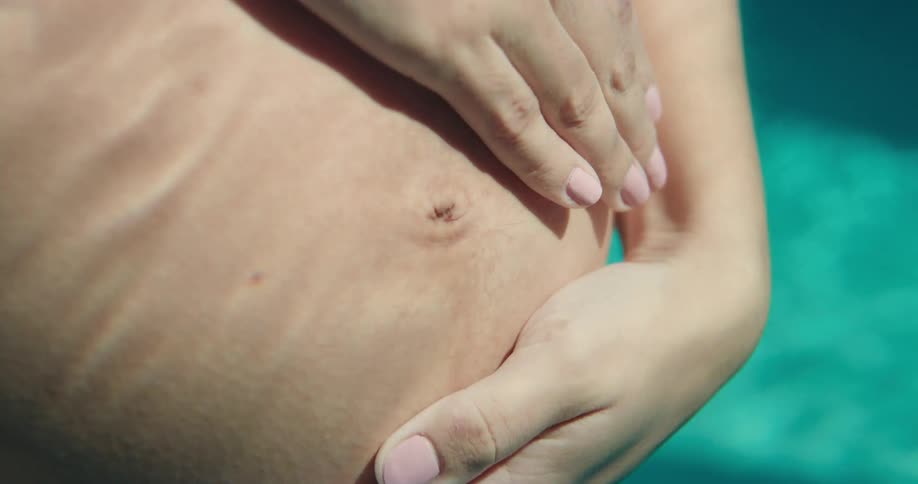 Underwater footage of a pregnant woman rubbing her belly inside a pool