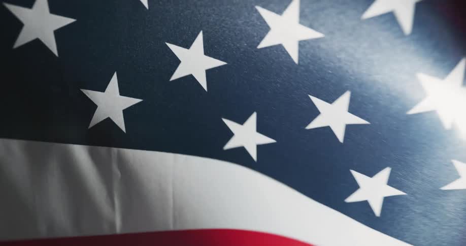 The american flag blowing and waving with light shining through