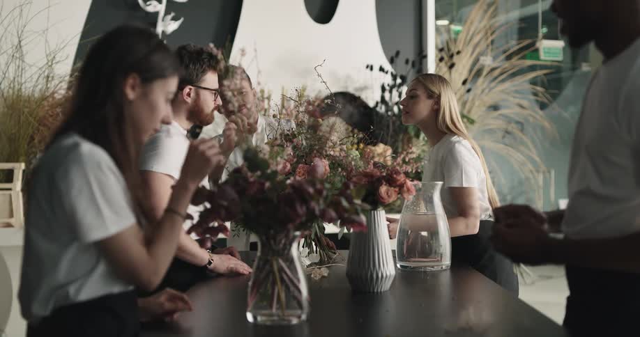 An employer instructs his team on proper flower arrangement styles in a shop