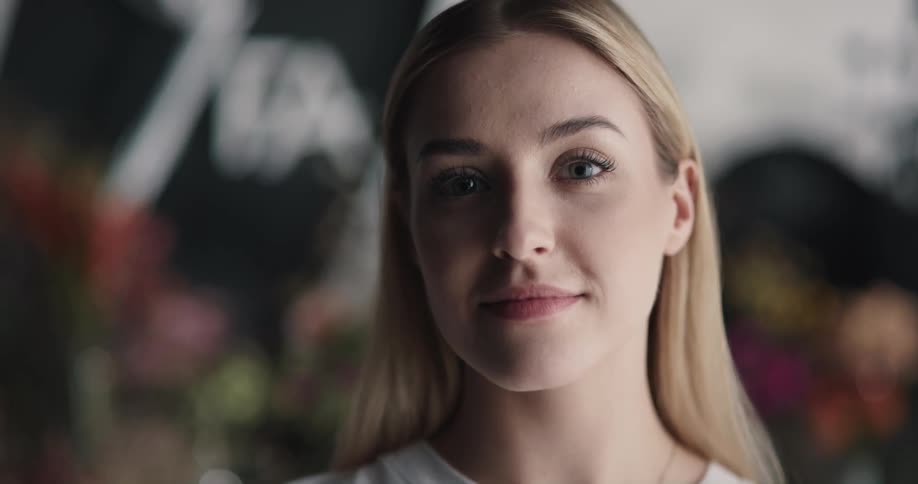 A woman is smiling and standing at a flower store