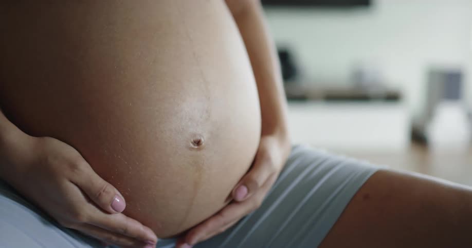 Pregnant woman with blue shorts works out at home