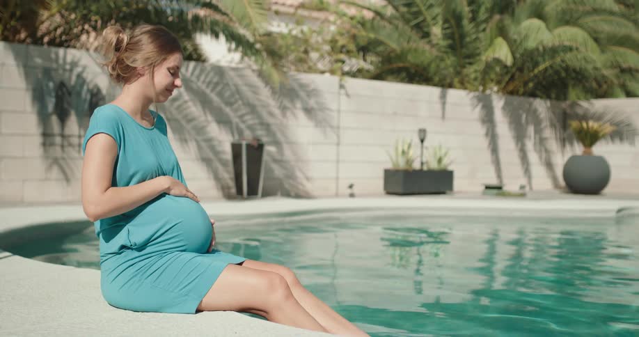 Pregnant woman is sitting by the pool