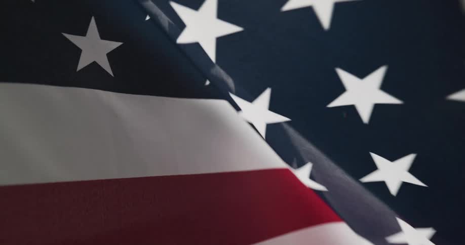 Tight shot of an american flag waving in the wind at night