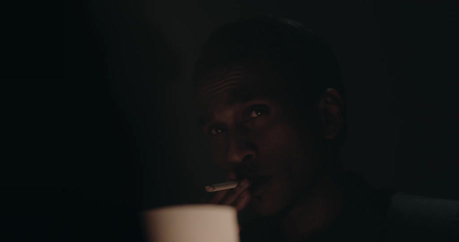 A man is talking to someone and smoking a cigarette