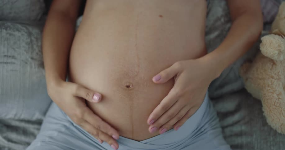 A woman rubs her belly in bed