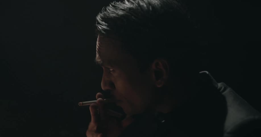 A man is smoking in a room and looking at documents