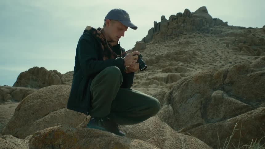A man is outdoors and taking pictures of landscapes