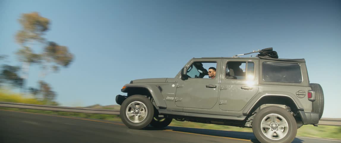 A man drives a vehicle along an inclined road on a hilly coastline during the day