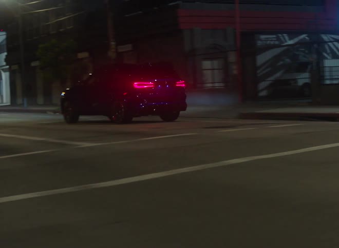 A vehicle travels across an intersection in a city at night