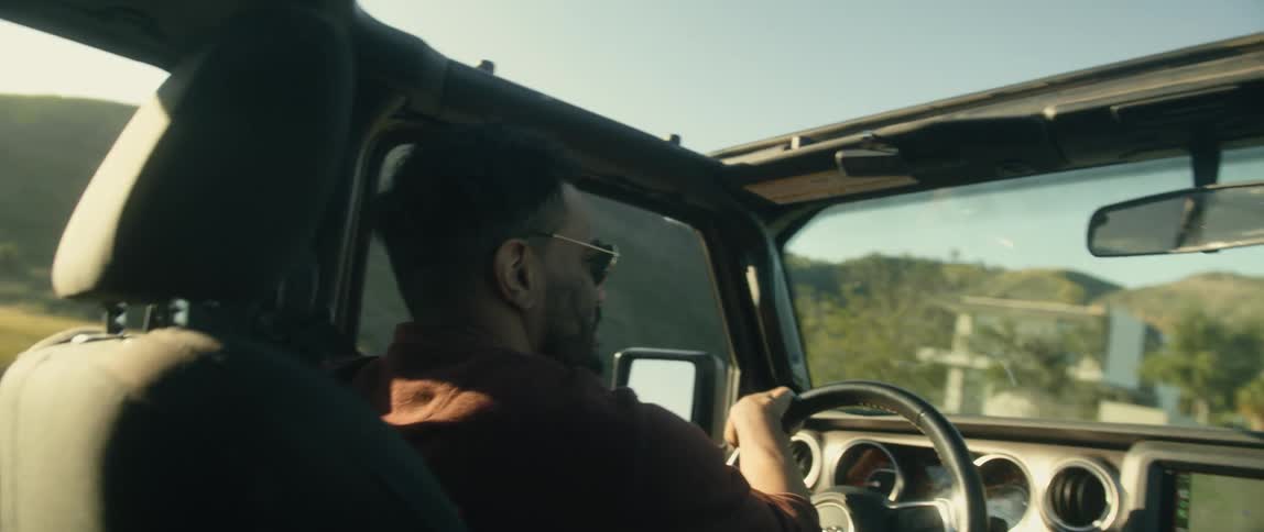 A man is driving a vehicle through a rural area at dusk