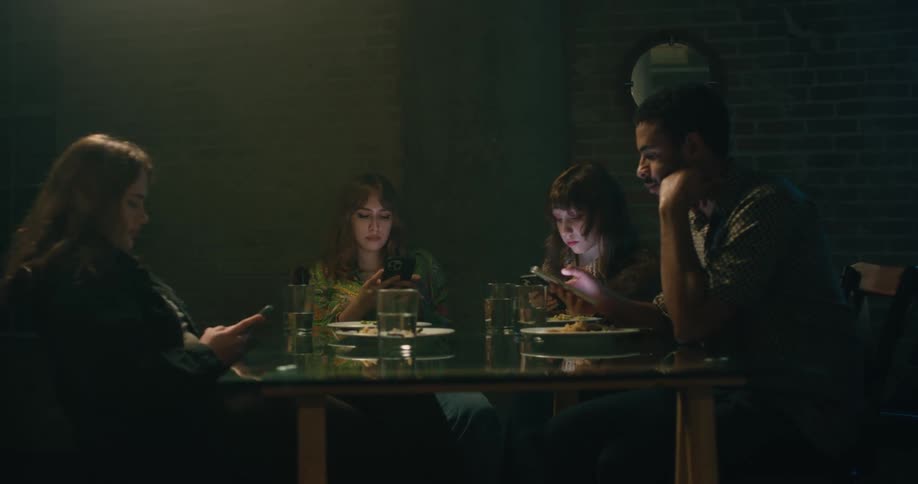 Friends are sitting at a table and are on there phone
