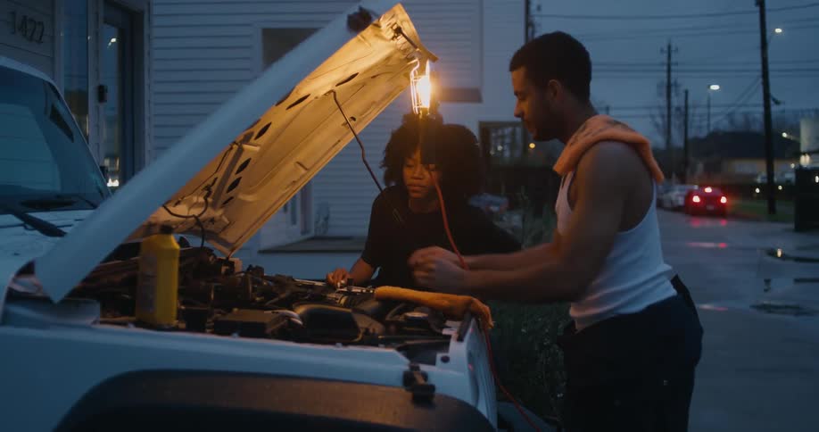 A young woman and man are fixing a car