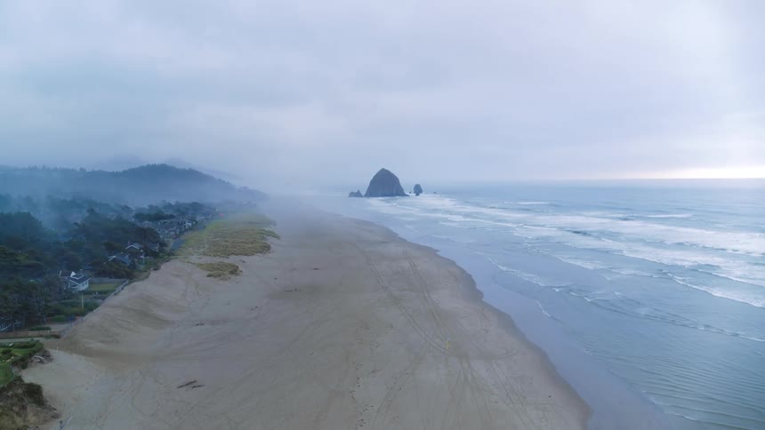 Aerial view of Pacific Ocean coastline with Haystack rock formation jutting out of the water