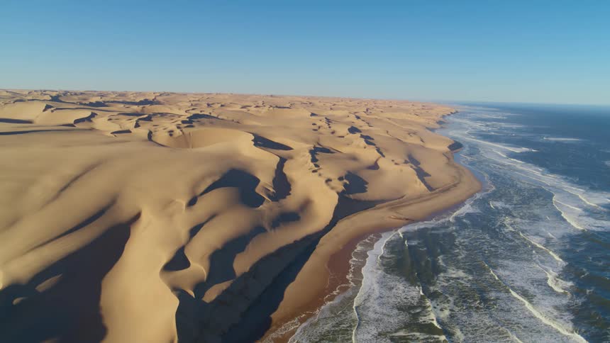 The coastline of expansive Namibian desert under a clear daytime sky