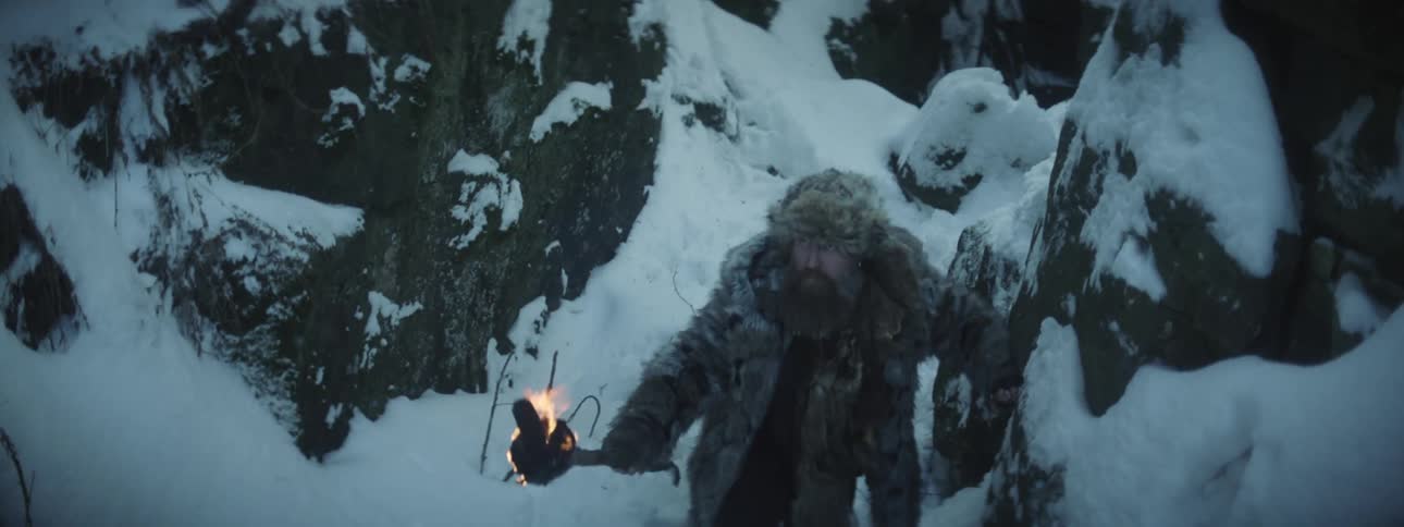 A man is hiking through an arctic area and holding a torch