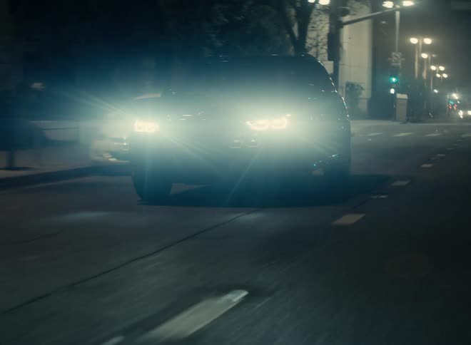A vehicle travels along a road through a city at night