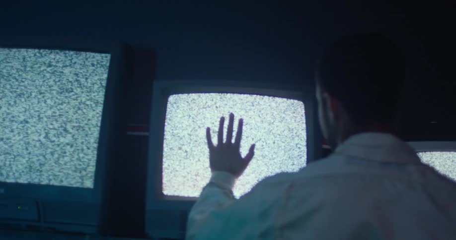 A young teenager is putting his hand on the television
