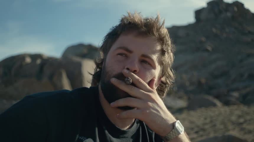 A man is smoking a cigar in the wilderness